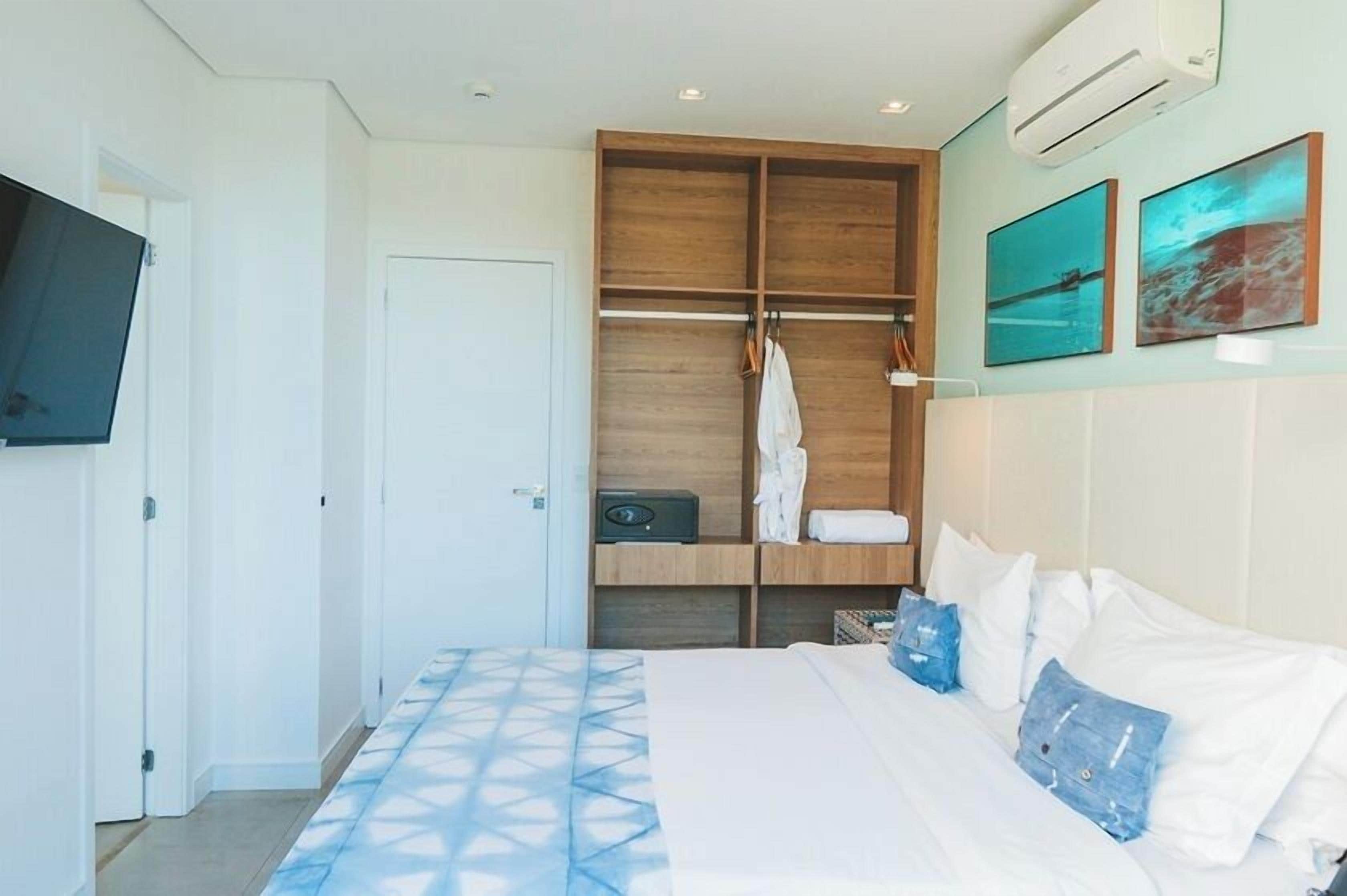 A bedroom with a bed, a wardrobe, and a television mounted on the wall.