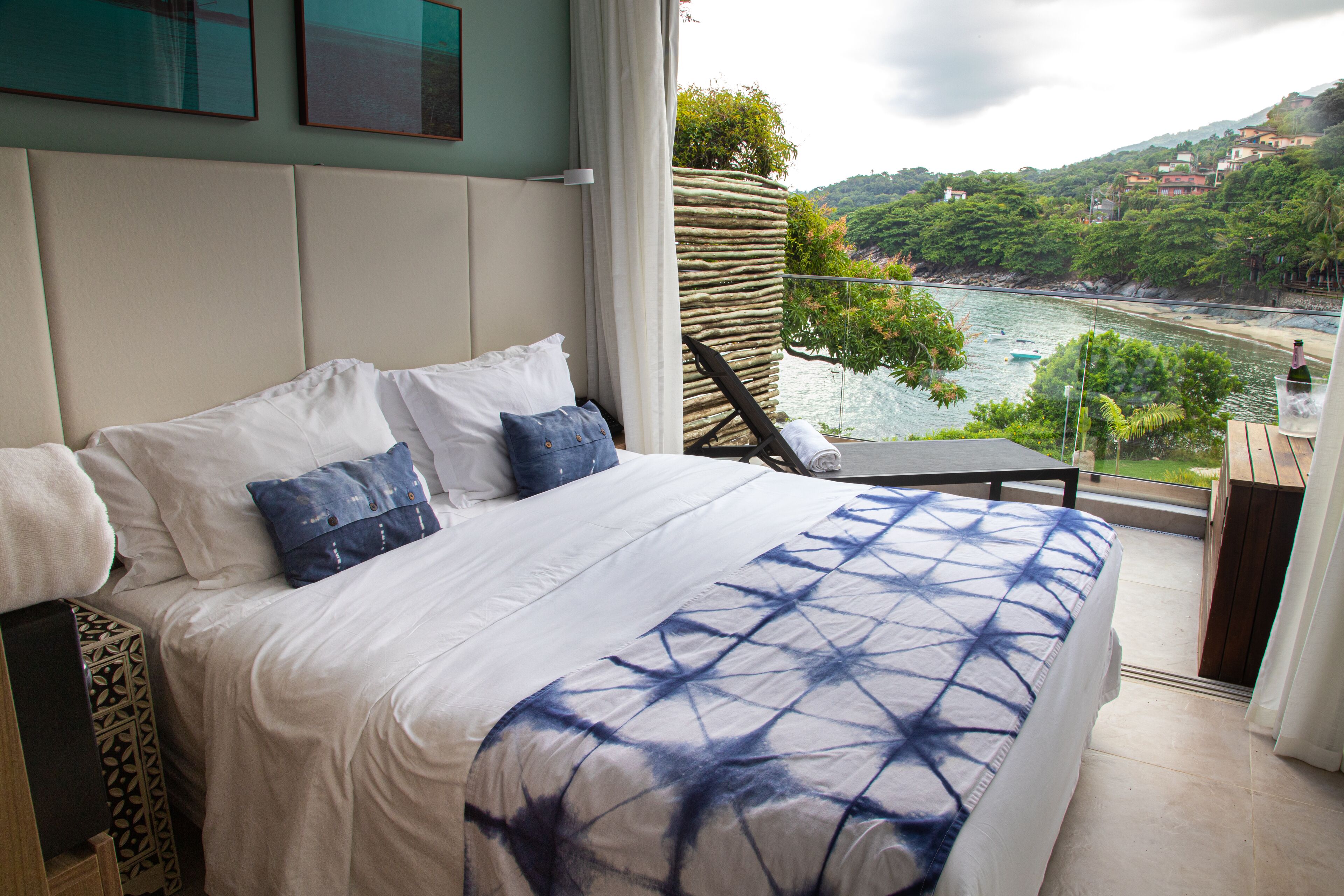 A bedroom with a large bed, a view of a river, and a balcony with a chair.