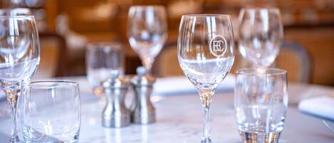 Una mesa de comedor dispuesta con copas de vino transparentes, un vaso de agua y un salero y pimentero.