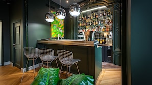 Zona de bar con mostrador, taburetes y una variedad de botellas.