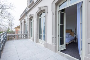 Una habitación de hotel con cama, mesita de noche y ventana con cortinas.