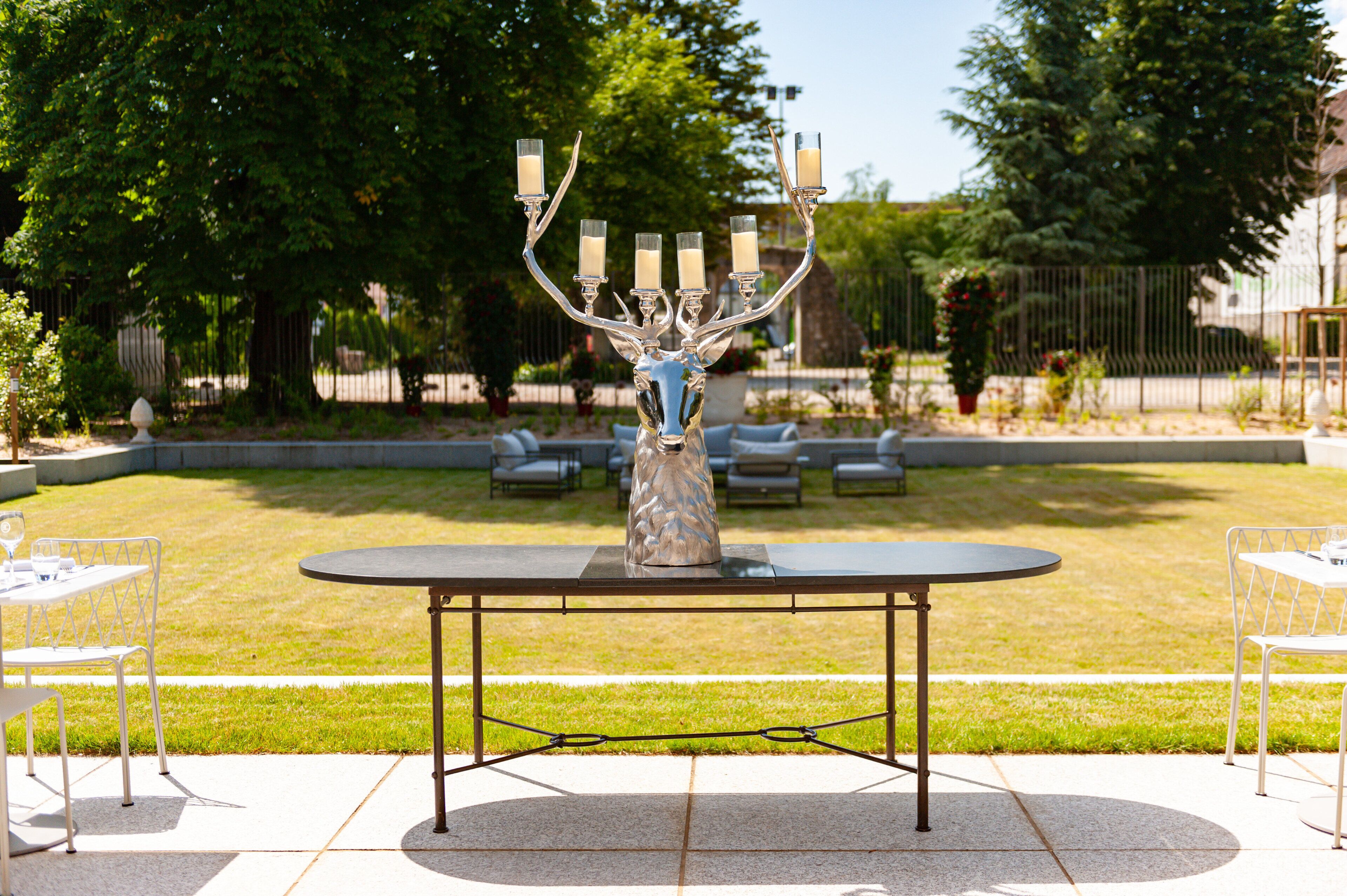 An outdoor patio with a round table, chairs, and a decorative metal candelabra with candles.