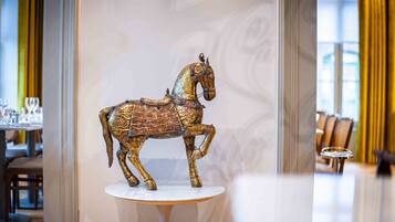 A decorative horse statue on a pedestal in a well-lit room with a modern interior design.