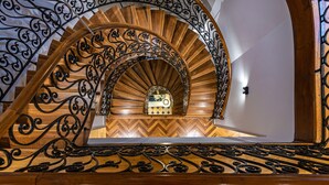 Una escalera de caracol con barandillas de metal negro ornamentadas y peldaños de madera.