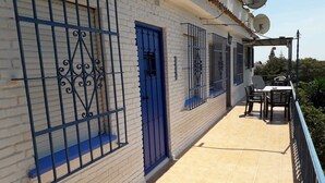 Un edificio con puerta azul, ventanas protegidas por barrotes y antenas parabólicas en el techo.