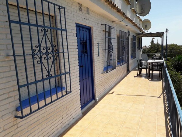 Un edificio con puerta azul, ventanas protegidas por barrotes y antenas parabólicas en el techo.