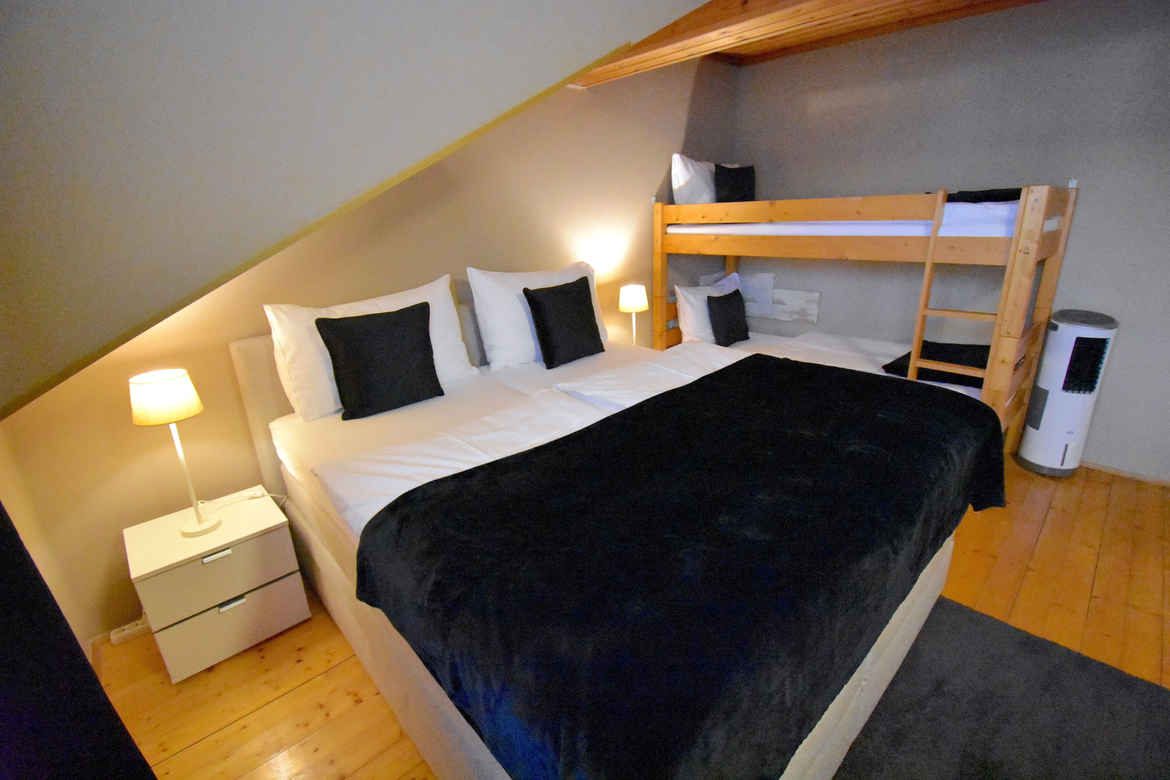 Ein Schlafzimmer mit Etagenbett, einem Einzelbett, einem Nachttisch mit Lampe und einem Heizgerät.