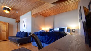 A bedroom with a bed, a sofa, a wooden ceiling, and a framed picture on the wall. - Hotel Jägerhof Wörthersee - Only Adults Official Partner Amoria Spa (Krumpendorf am Woerther See)