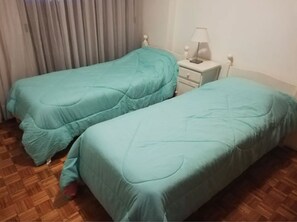 A room with two single beds, a nightstand with a lamp, and a window with curtains. - Recoleta Apartment - 2 Dormitorios (Buenos Aires)