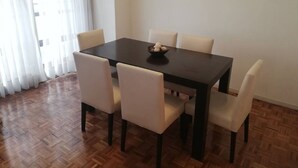 A dining area with a dark wooden table and six chairs, a bowl of snacks on the table, and a painting on the wall. - Recoleta Apartment - 2 Dormitorios (Buenos Aires)