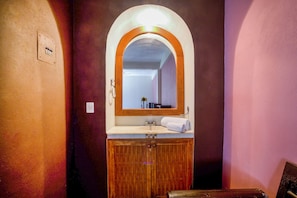 Un baño con tocador de madera, un espejo y un lavabo.