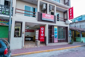 Un hotel llamado OYO Hotel Posada LYS con una fachada moderna, ventanas amplias y señalización llamativa.