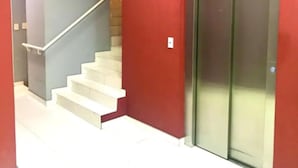 A staircase with a handrail leading to a red wall and an elevator. - Palermo Soho Apartment 2 (Buenos Aires)