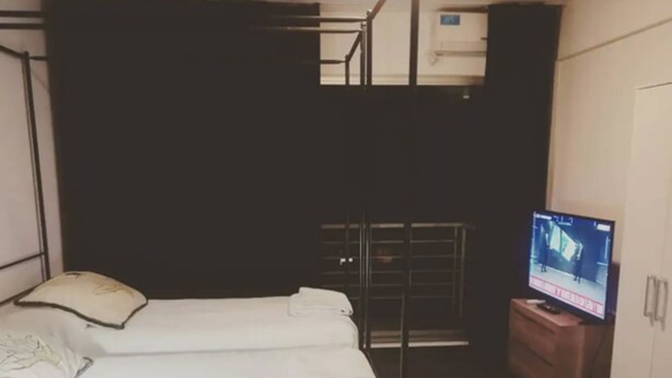 A small, compact hotel room with a single bed, a television, and a wardrobe. - Palermo Soho Apartment 2 (Buenos Aires)