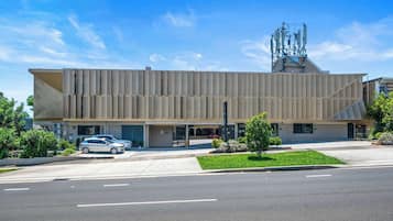 Un edificio moderno con techo plano, amplia zona de estacionamiento y cielo despejado.