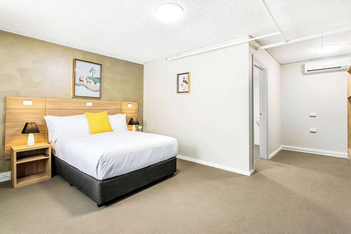 A bedroom with a bed, nightstands, and a door.