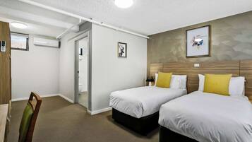 A hotel room with two beds, a desk, and a chair.