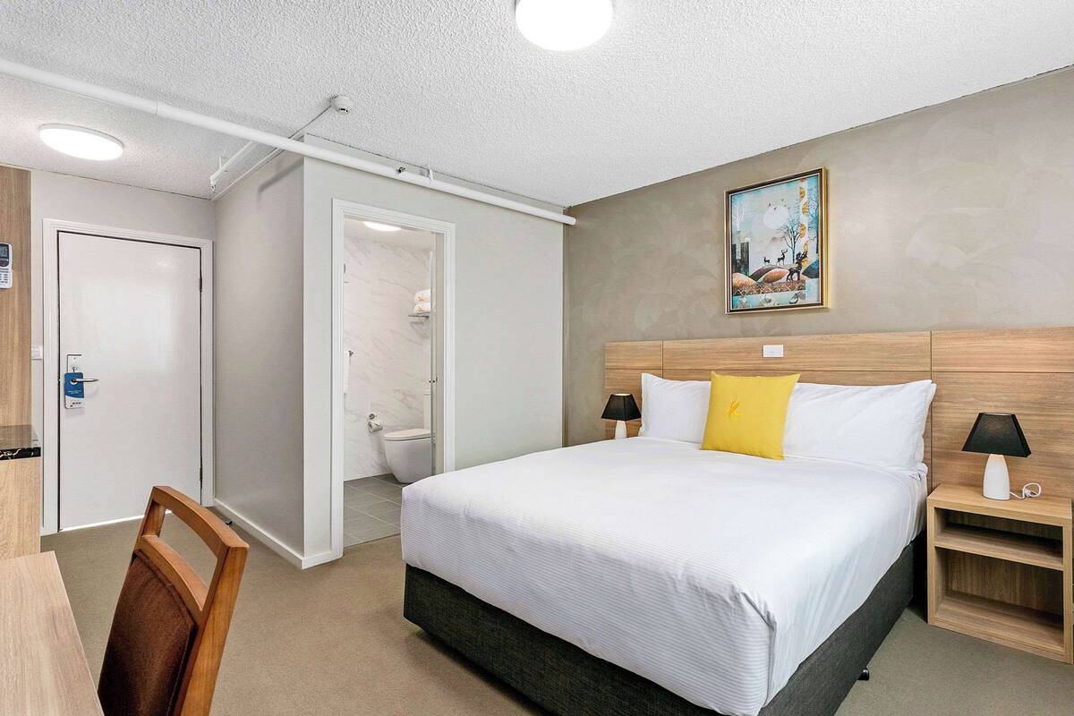A hotel room with a large bed, bedside tables, a desk, and a chair.