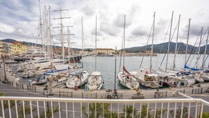 A marina with multiple sailboats docked, a waterfront promenade, and buildings in the background. - Appartamenti La Calata (Portoferraio)
