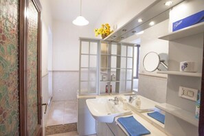 Casa de banho com duas pias, um espelho e um armário com produtos de higiene.
