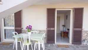 An outdoor patio with a table and chairs, a vase with flowers, and a stone floor. - Casa Malva (Portoferraio)
