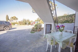 Zona exterior coberta amb taula i cadires, un cotxe aparcat i plantes en testos.