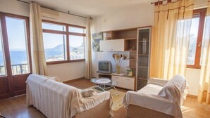 A room with two beds, a small table, a TV, and a view of the sea. - Scoglietto (Portoferraio)