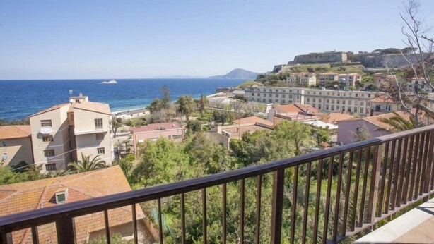 A coastal town with buildings, a sea view, and a fort on a hill. - Scoglietto (Portoferraio)