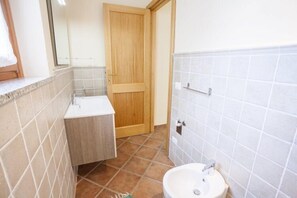 A bathroom with a wooden door, white sink, and tiled walls.