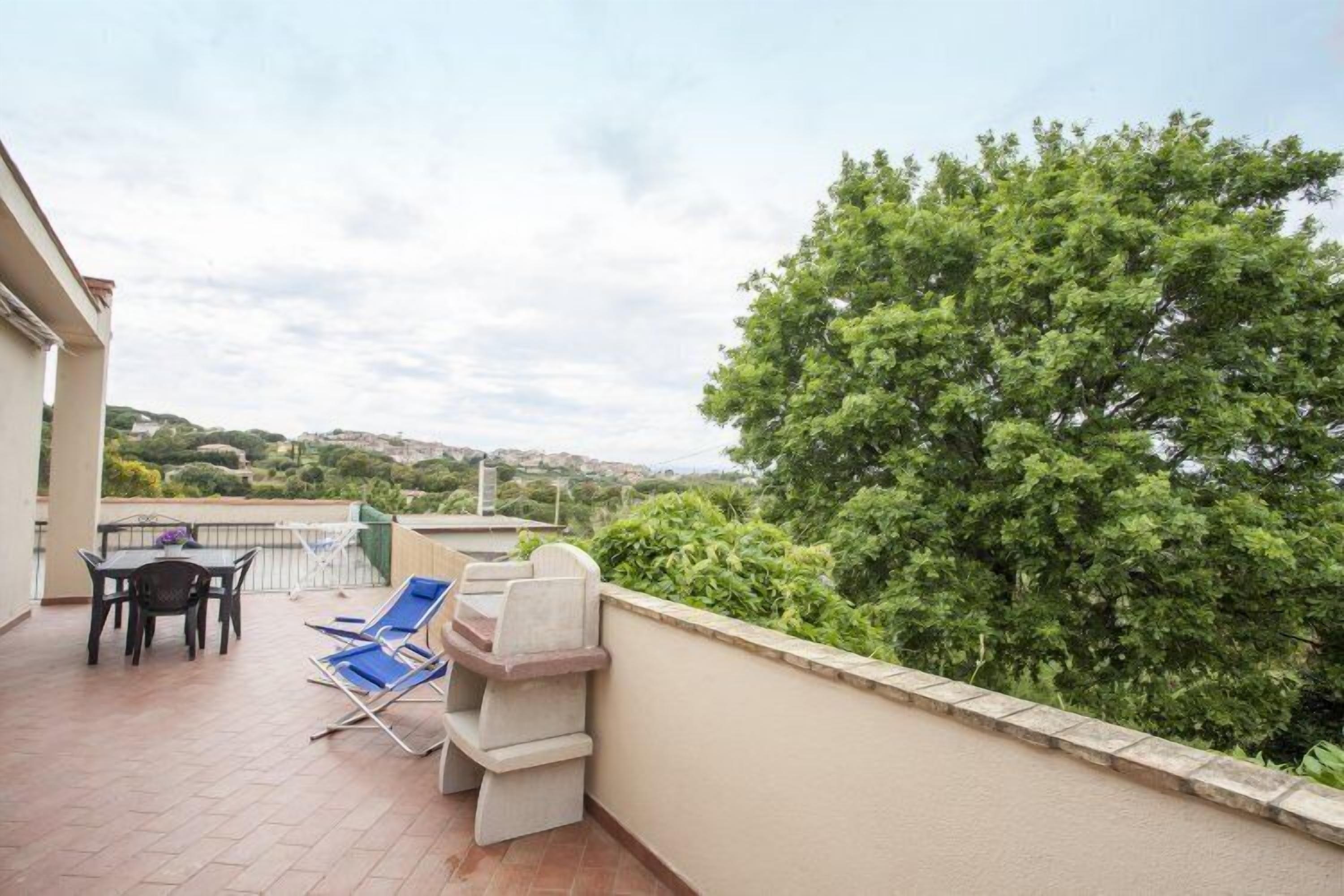 A balcony with a table, chairs, and a grill.