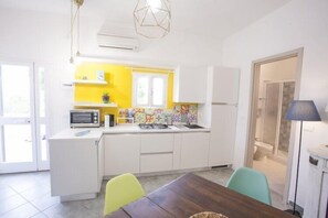 A compact kitchen with white cabinets, a microwave, and a colorful backsplash. - Bilocale Koala (Capoliveri)