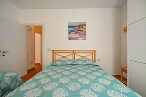 A bedroom with a bed, a door, and a painting on the wall.