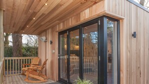 A wooden deck with a rocking chair and a glass door leading to an interior space. - Thatched Eaves (Ringwood)