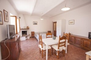 Un accogliente soggiorno con camino, un tavolo da pranzo con sedie e un televisore su un mobile in legno.