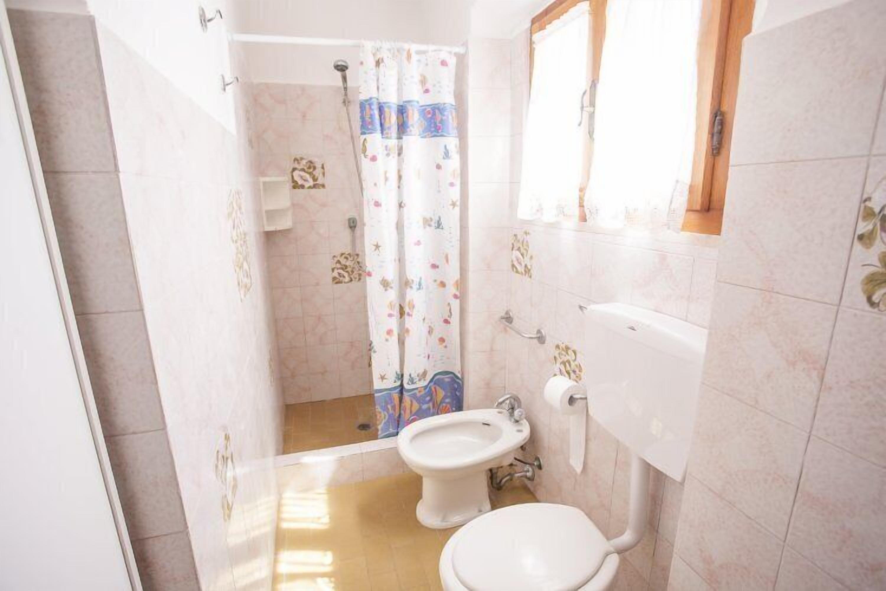 A bathroom with a shower, a bidet, and a toilet.