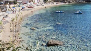 Ein Strand mit klarem Wasser, Booten und Menschen.