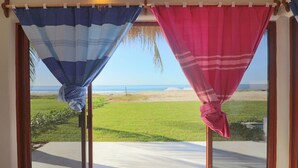 Ein Zimmer mit Blick auf den Strand, durch Vorhänge zu sehen.
