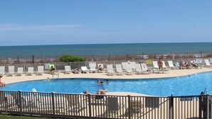 A pool area with lounge chairs and a sign indicating pool hours. - Birdie's Beachfront I - The only Oceanfront Condo to be at Myrtle Beach Resort (Myrtle Beach)