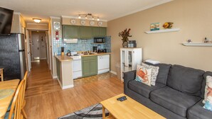 A compact living space with a kitchen, dining area, and a gray sofa. - Birdie's Beachfront I - The only Oceanfront Condo to be at Myrtle Beach Resort (Myrtle Beach)