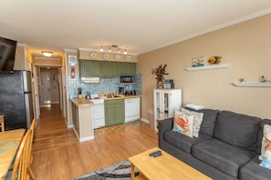 A compact living space with a kitchen, dining area, and a gray sofa.