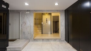 A modern interior with a marble floor, a door with a diamond-shaped handle, and a staircase leading to an upper level. - Chiado Patio Apartment (Lisboa)