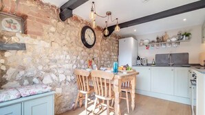 Une cuisine rustique avec un mur en pierre, des chaises en bois, une table à manger et un réfrigérateur moderne.