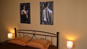 Une chambre à coucher avec un lit, deux lampes fixées au mur et deux œuvres d’art encadrées.