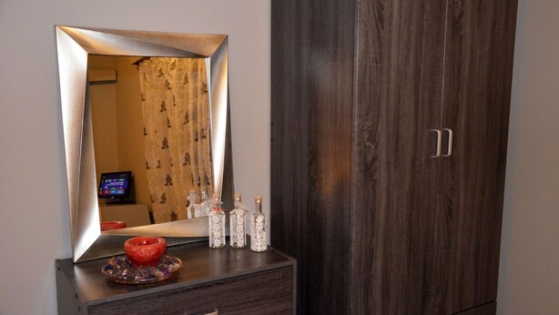 Un miroir avec un cadre en bois, une armoire en bois foncé et une petite table ornée d’objets décoratifs.