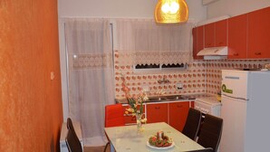 Une cuisine de taille réduite comprenant une table à manger, des chaises, un réfrigérateur et une cuisinière.