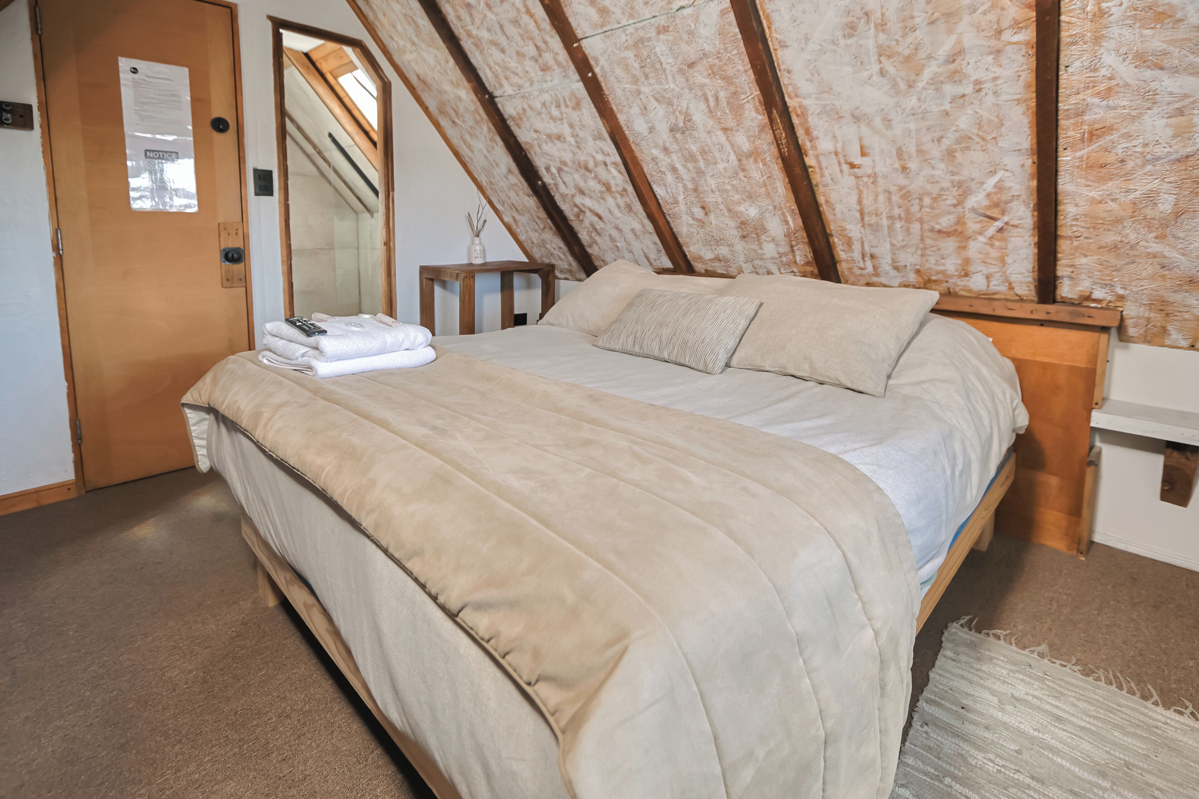 A bedroom with a bed, wooden headboard, and a small bedside table.