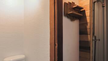A bathroom with a white toilet, wooden floor, and a wooden door.