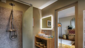 Een moderne badkamer met een douchecabine van glas, een houten wastafelmeubel en een spiegel erboven.