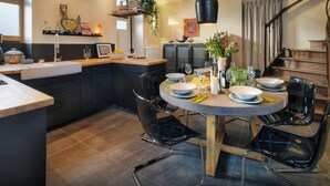 Een moderne keuken met een centraal eiland, zwarte stoelen en een eettafel voor vier personen.
