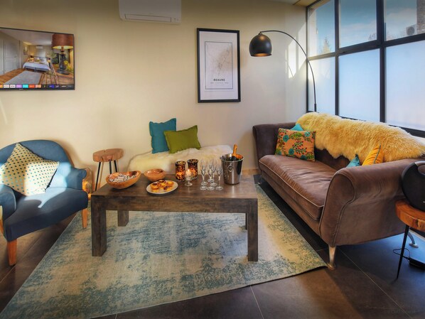 A modern living room with a sofa, armchair, coffee table, and a framed map on the wall.